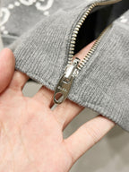 Close-up of grey hoodie zipper pull and ribbed cuff with GG-style pattern