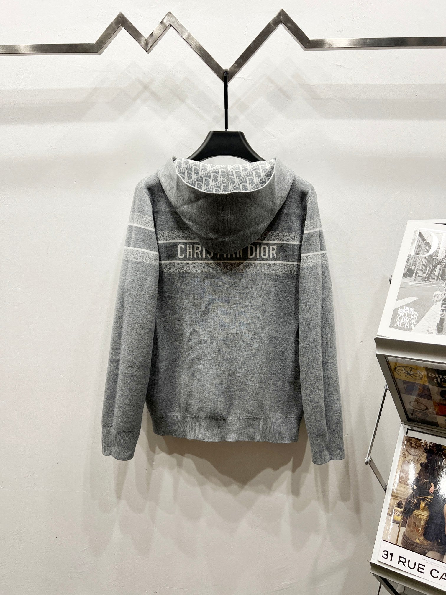 Gray hoodie with hood up, back logo text across shoulders, full-zip