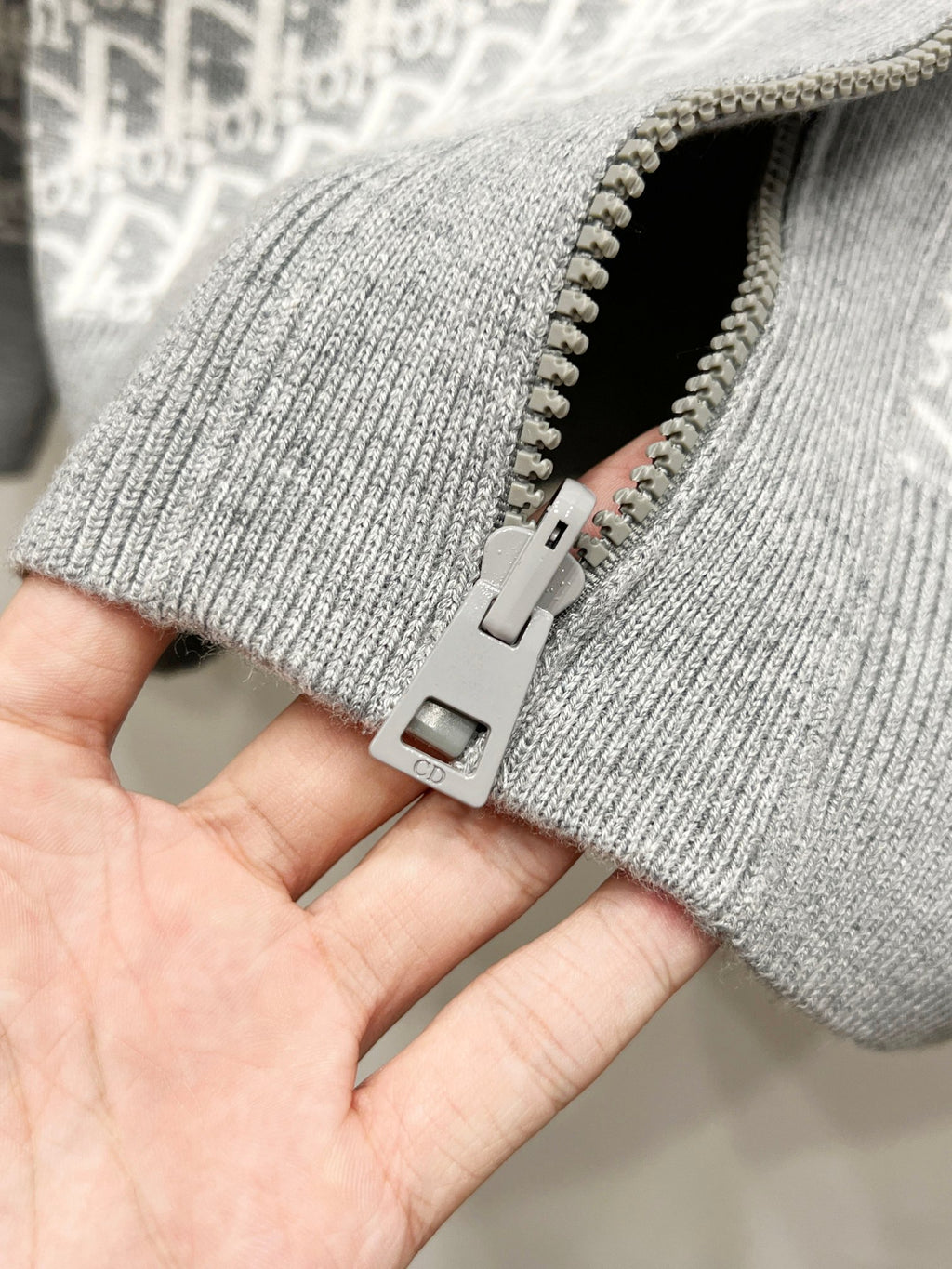 Gray knit hoodie cuff with metal zipper and pull tab