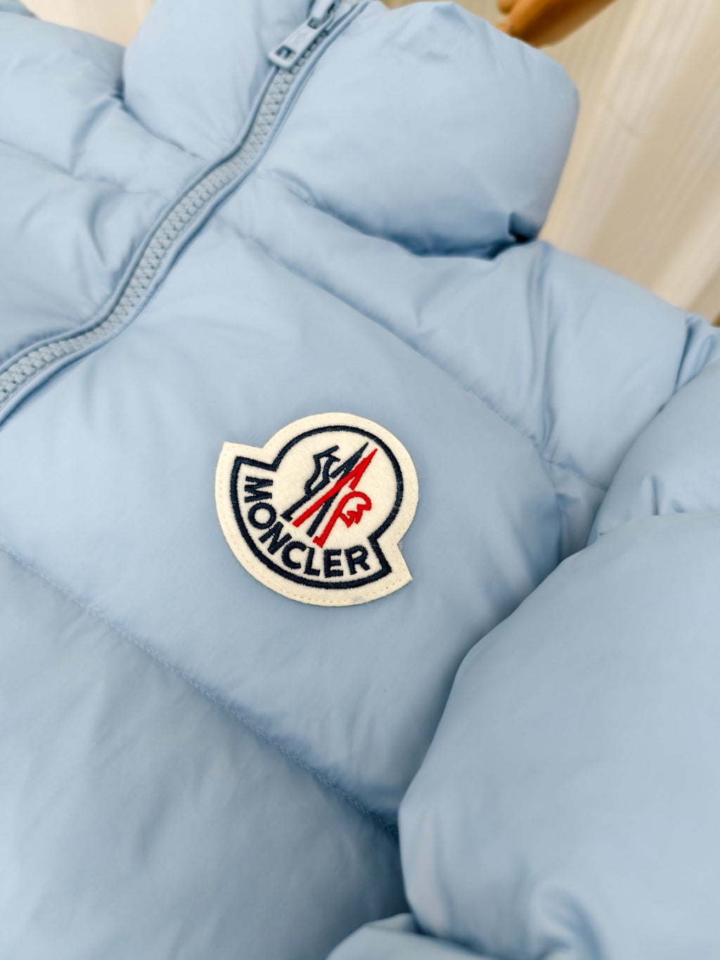 Light blue puffer jacket with Moncler logo crest patch on chest