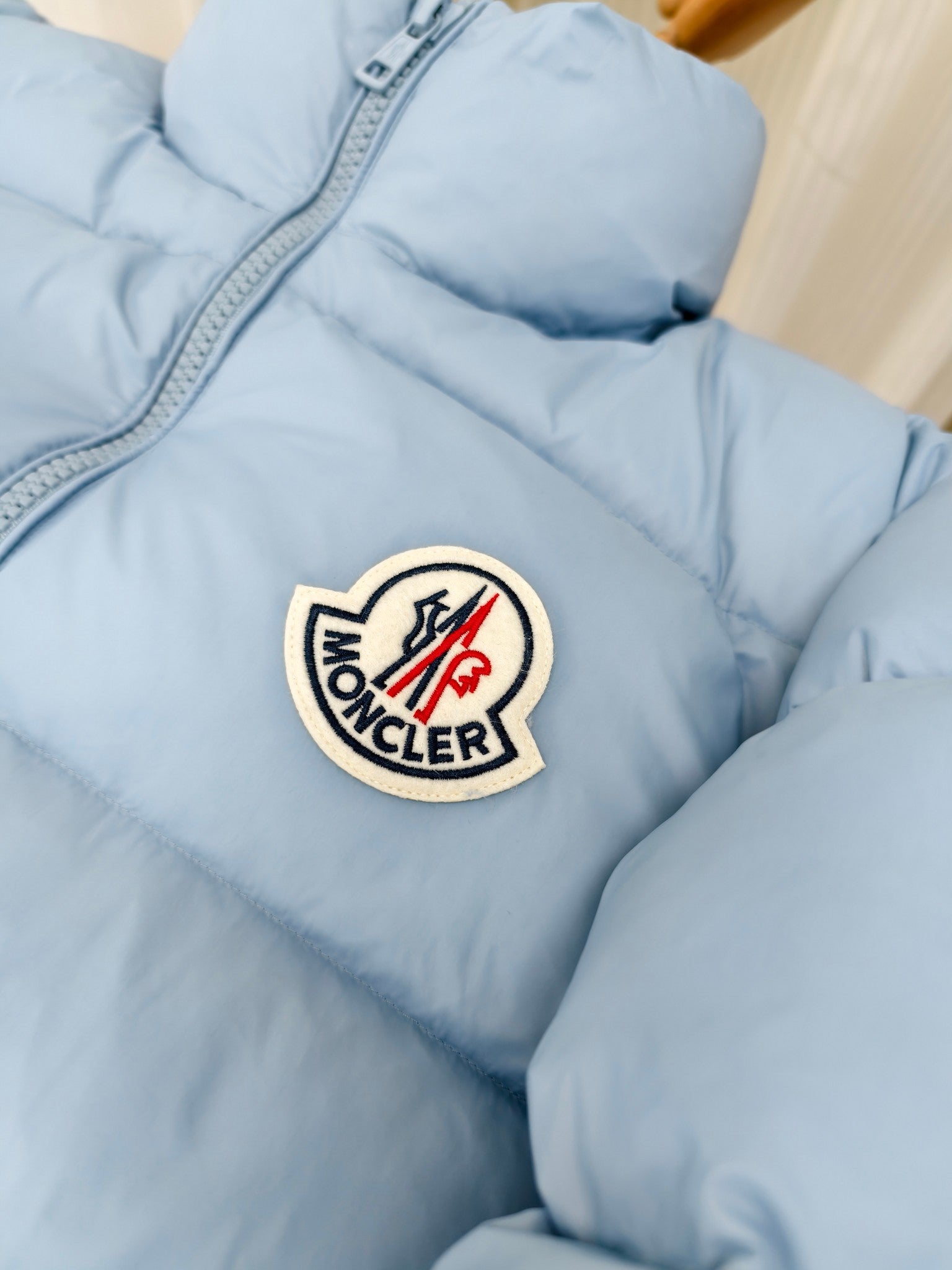 Light blue puffer jacket with Moncler logo crest patch on chest