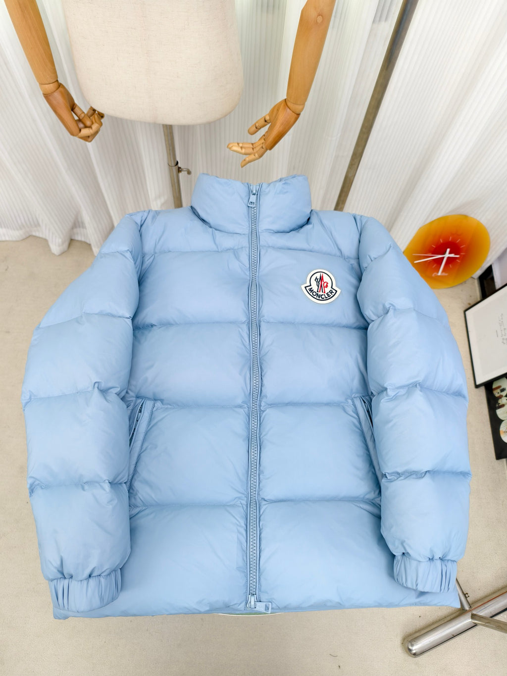 Light blue puffer jacket with zip front and Moncler logo patch on chest