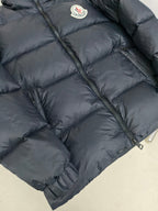 Moncler dark puffer jacket close-up of diagonal quilting and front zipper