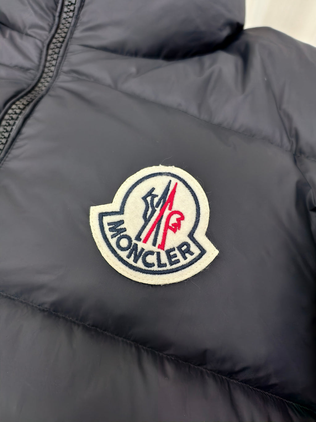 Moncler dark puffer jacket with large embroidered logo patch on chest