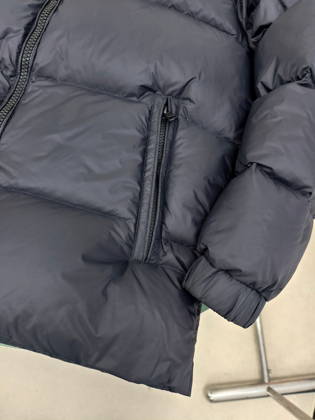 Moncler dark puffer jacket sleeve and side with ribbed cuffs and full-length zipper