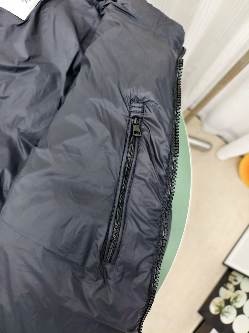 Moncler dark puffer jacket side view with zippered pocket and quilted texture