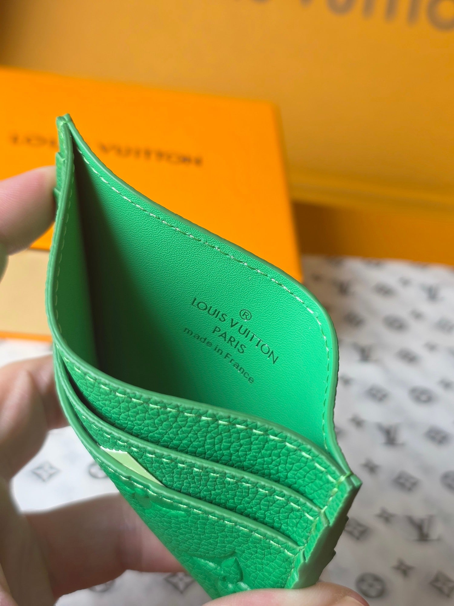 Louis Vuitton green embossed mini bag opened in hand showing interior logo print