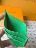 Louis Vuitton green monogram card holder held open, showing interior lining and stitching