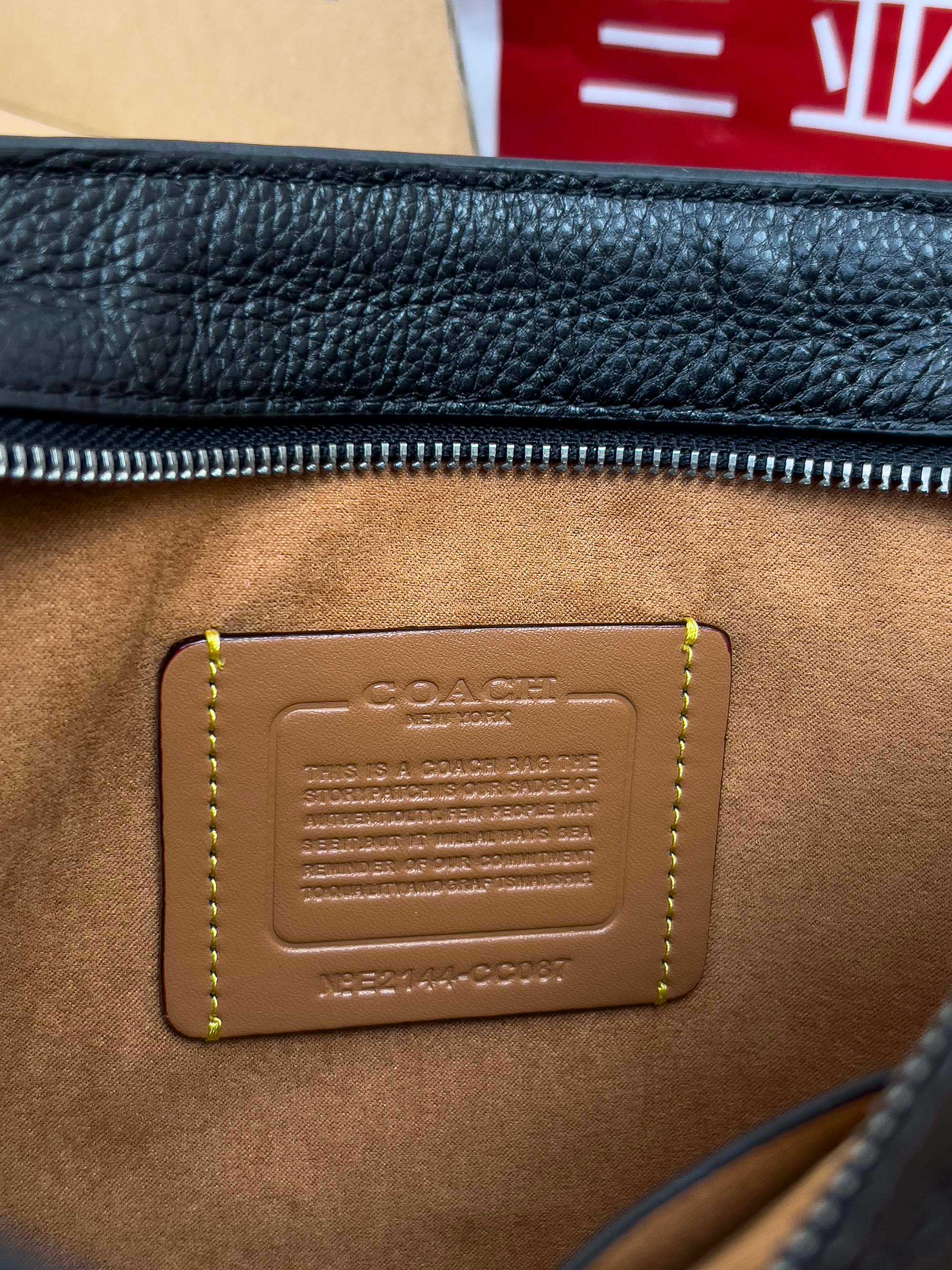 Close-up of COACH brown leather patch with embossed logo on bag