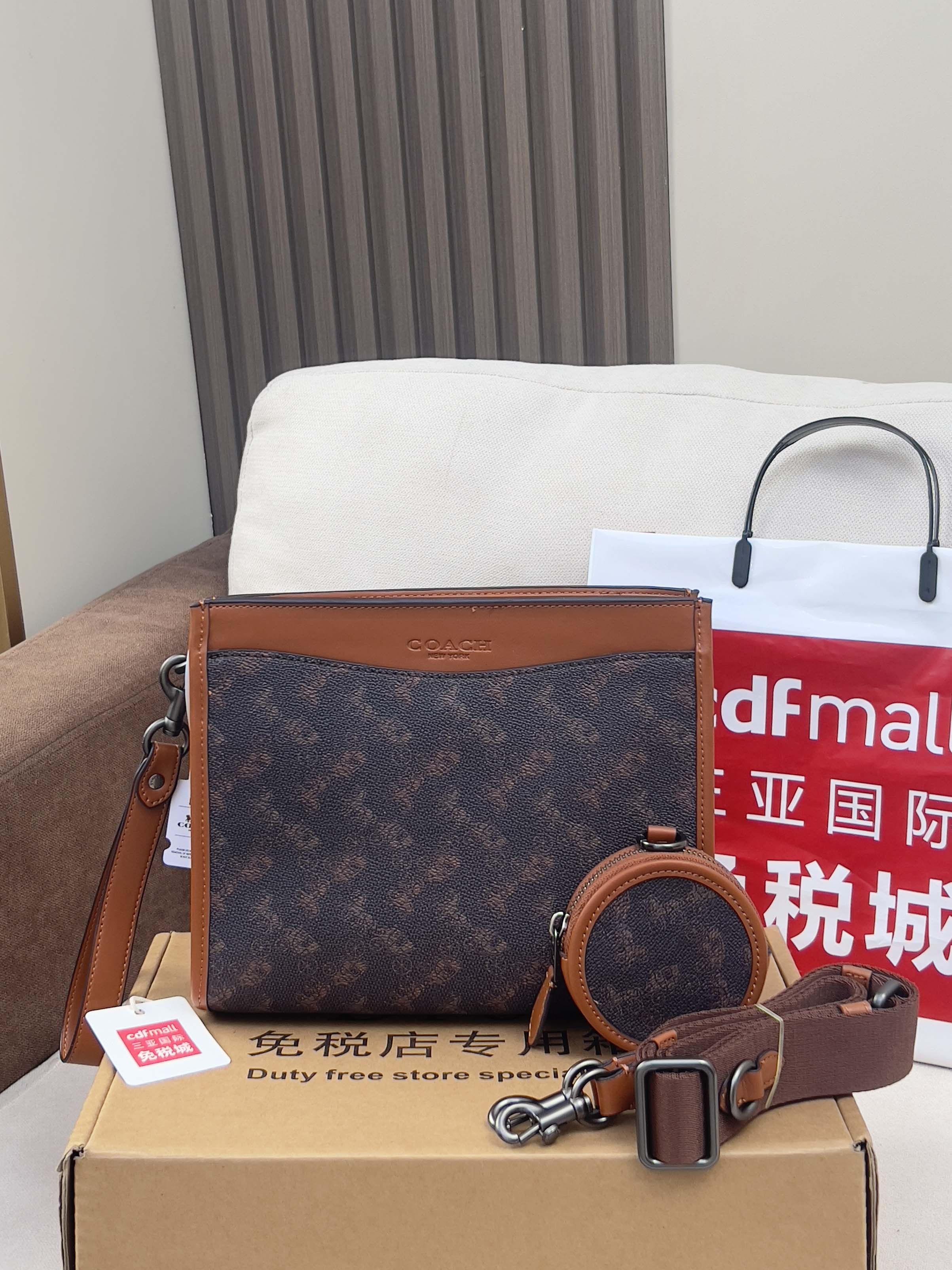 Coah bag with dark monogram body, brown leather crossbody strap and zip top