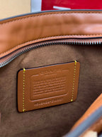 Coah bag tan leather brand patch with embossed text and stitched border on brown trim