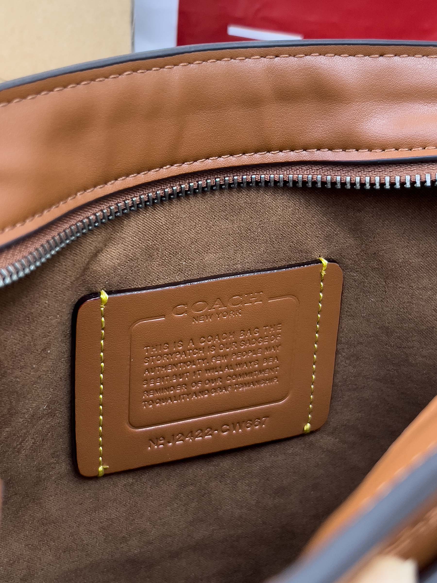 Coah bag tan leather brand patch with embossed text and stitched border on brown trim
