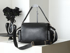 Black leather duffel-style bag with shoulder strap and gold hardware