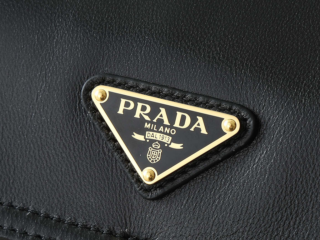 Black leather bag corner with triangular PRADA logo metal plaque