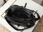 Black leather crossbody bag laid open with zip pockets and gold zippers