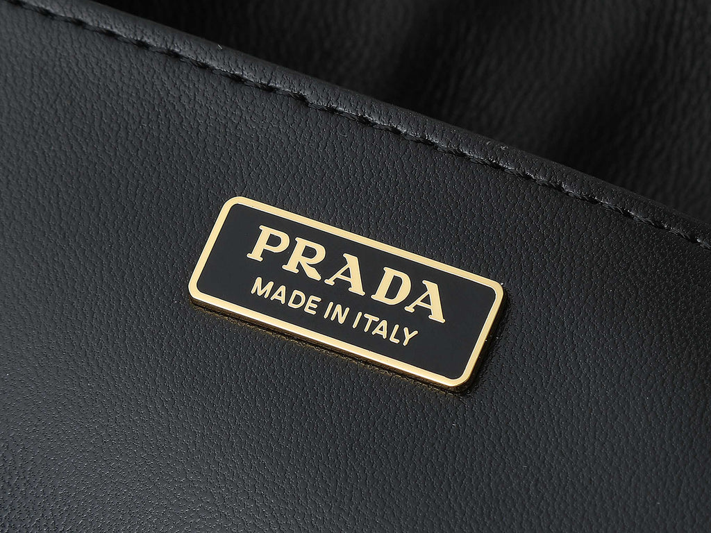 Black leather tag with gold trim reading PRADA and MADE IN ITALY
