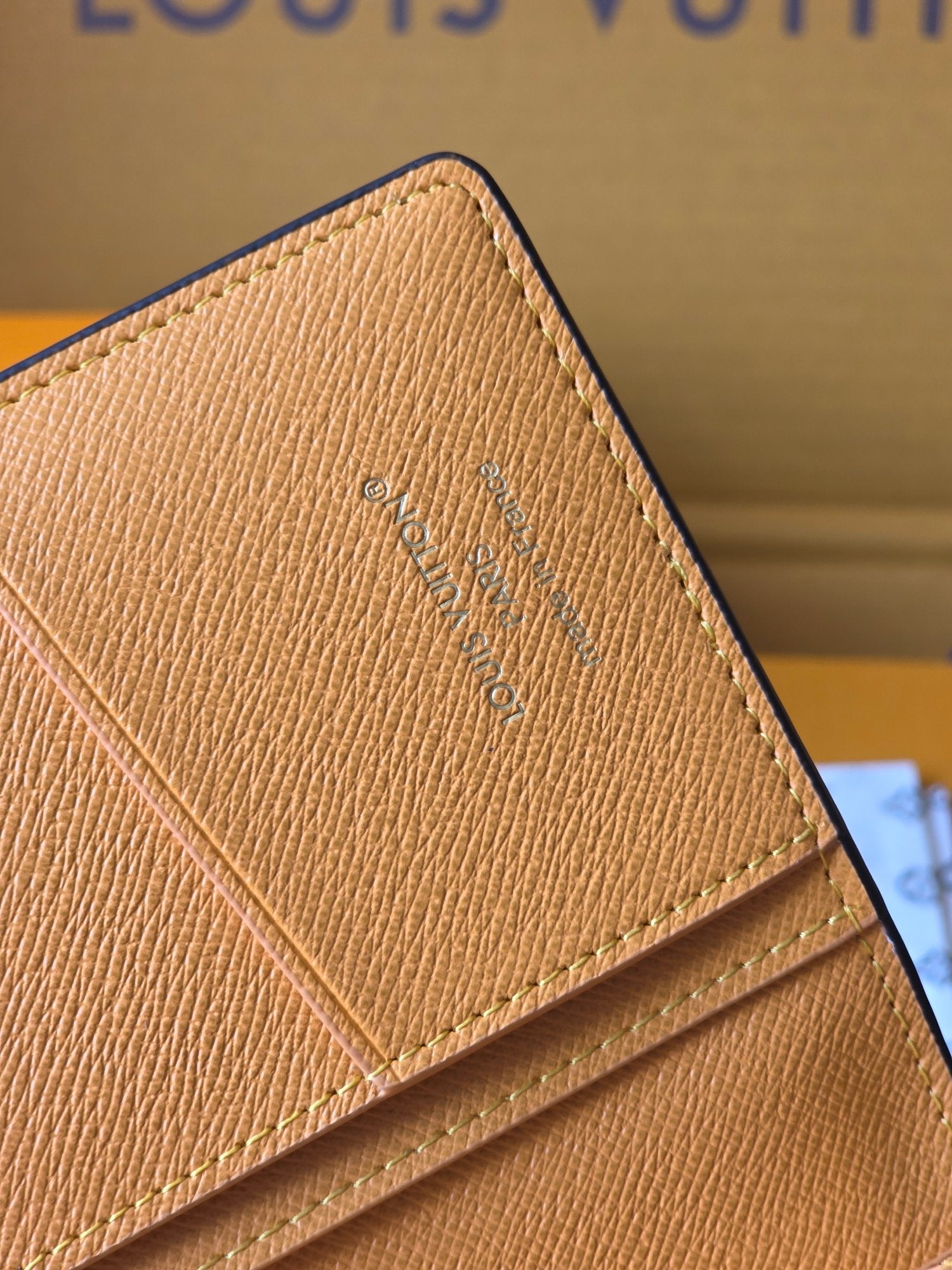Small card holder corner close-up with embossed Louis Vuitton monogram on tan leather