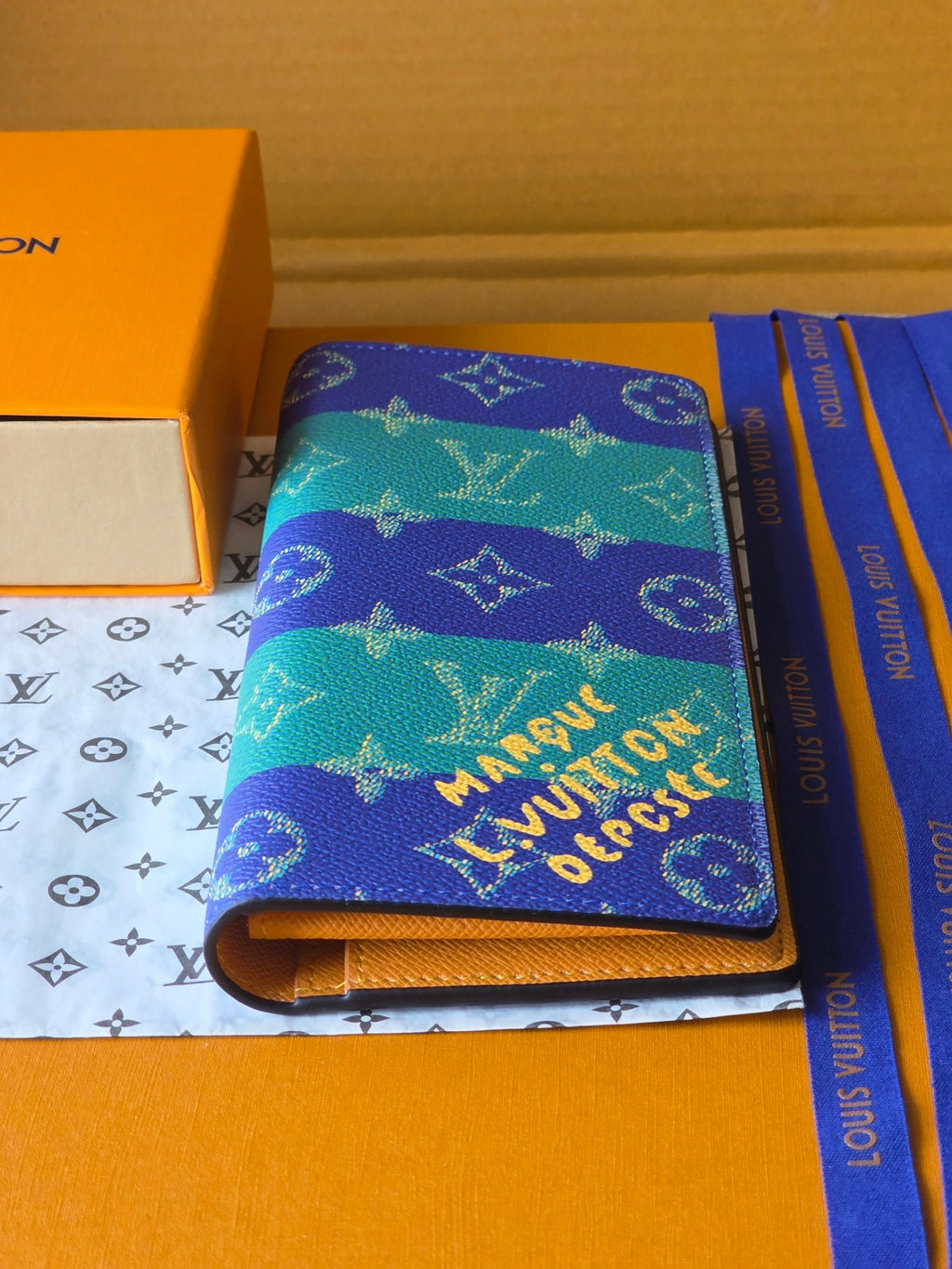 Small card holder with blue-and-teal monogram print, open edge and gold zipper pull