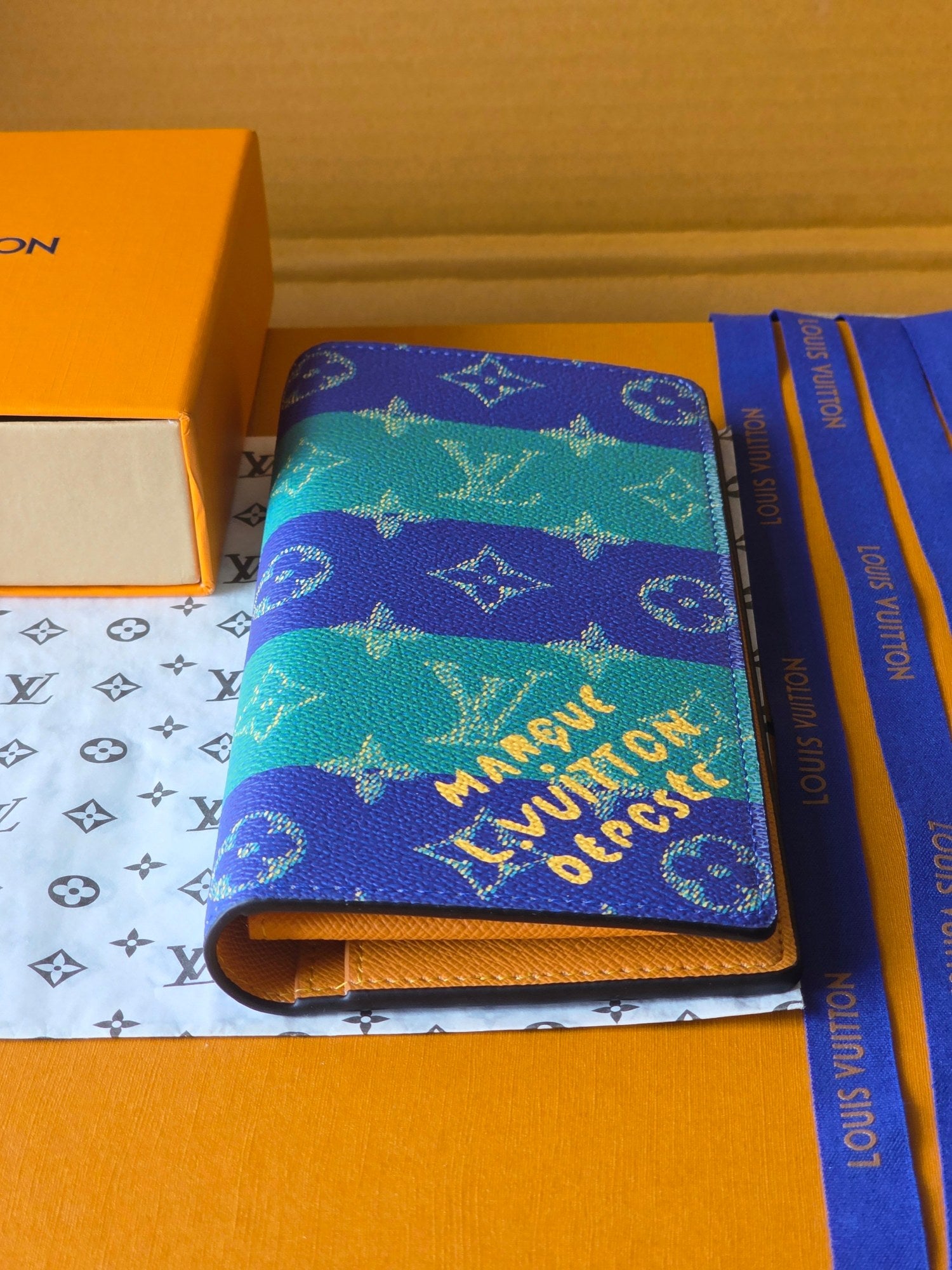 Small card holder with blue-and-teal monogram print, open edge and gold zipper pull
