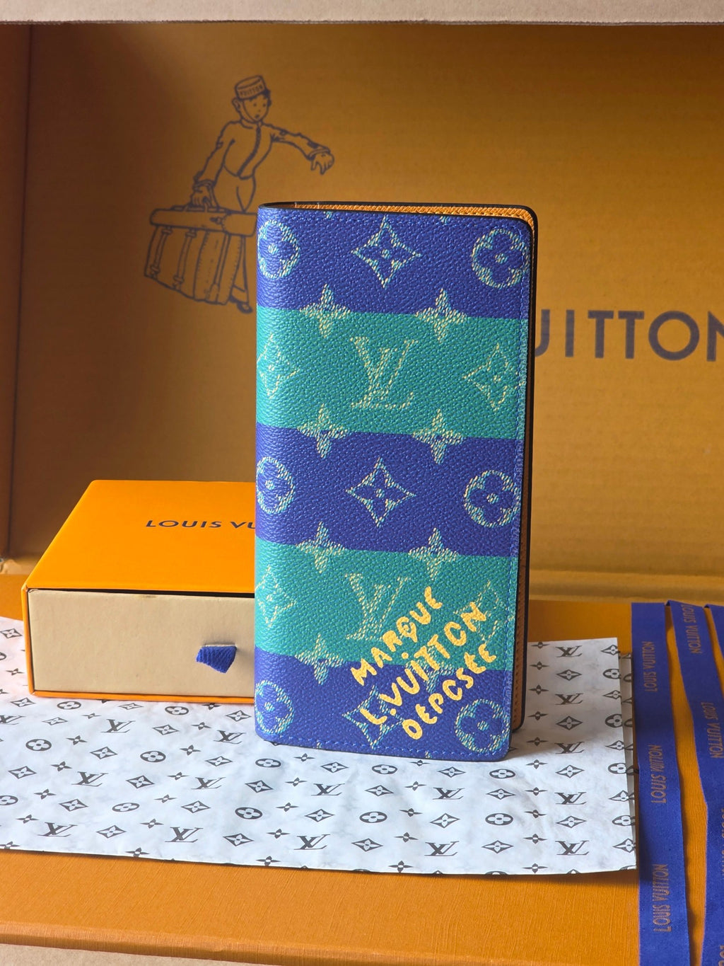 Small card holder with blue-and-teal monogram print, zip closure, pebbled texture