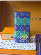Small card holder with blue-and-teal monogram print, zip closure, pebbled texture