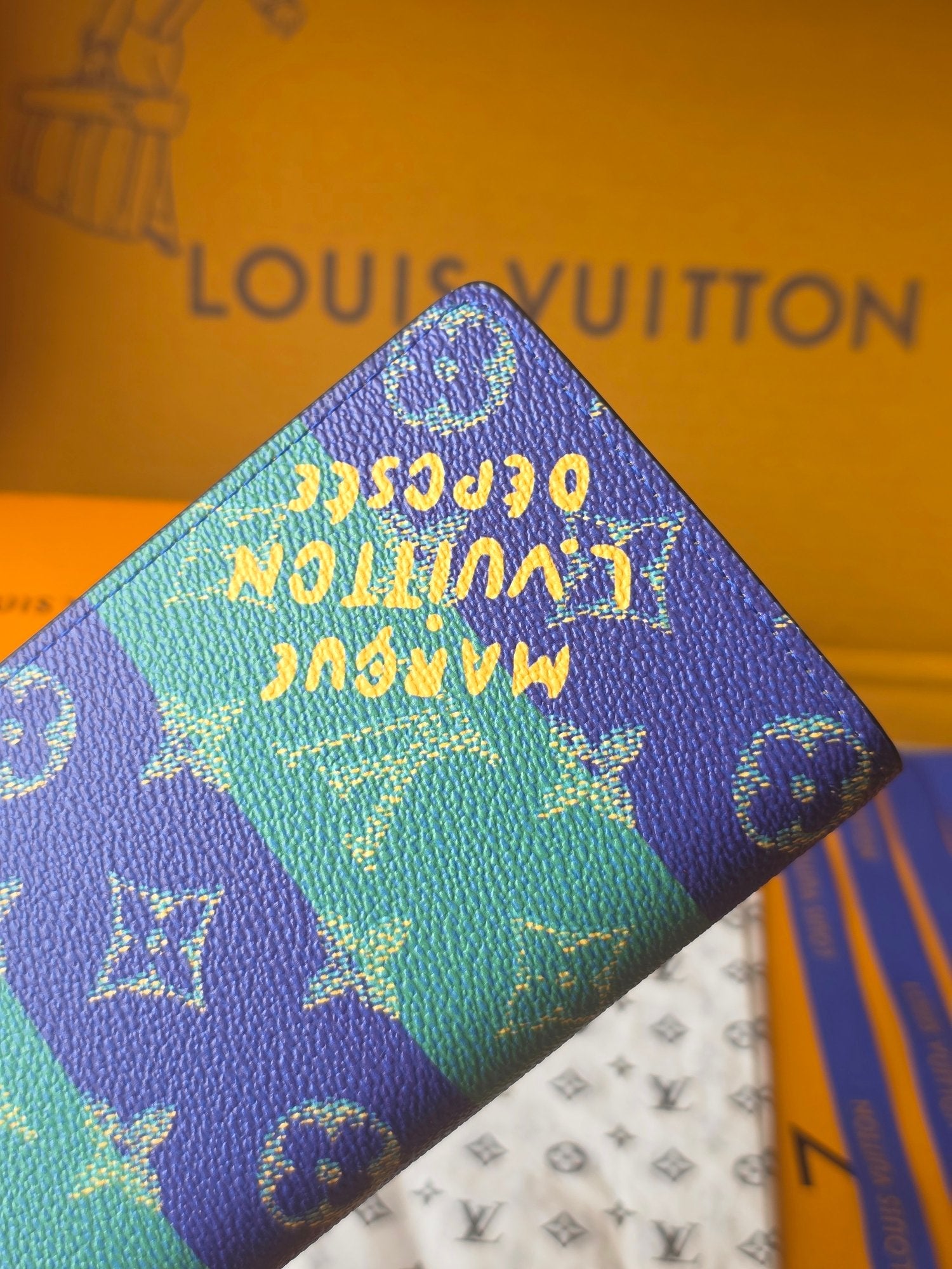 Small card holder top corner close-up with blue-and-teal monogram pattern