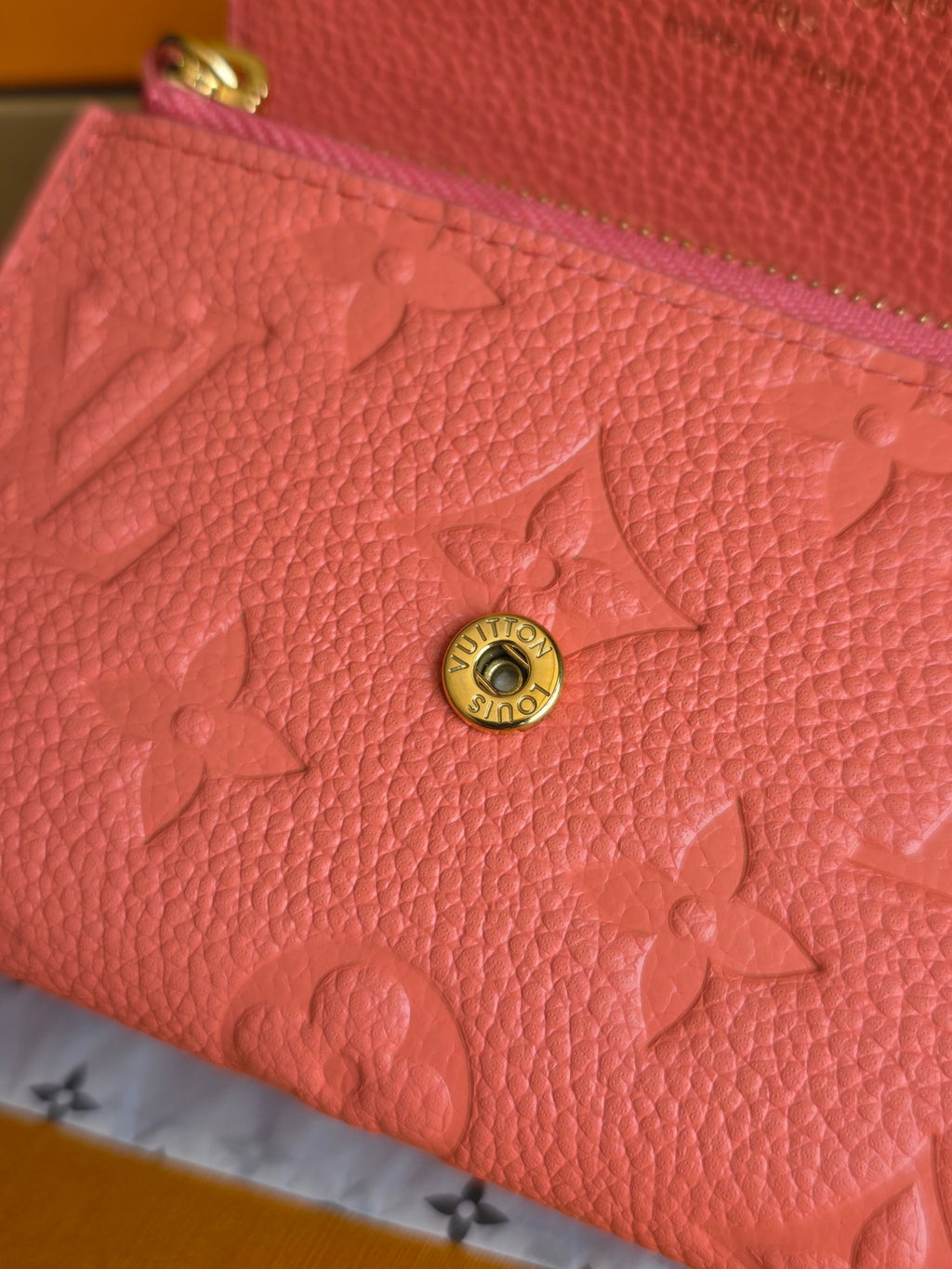 Louis Vuitton pink leather wallet close-up with embossed monogram and round button
