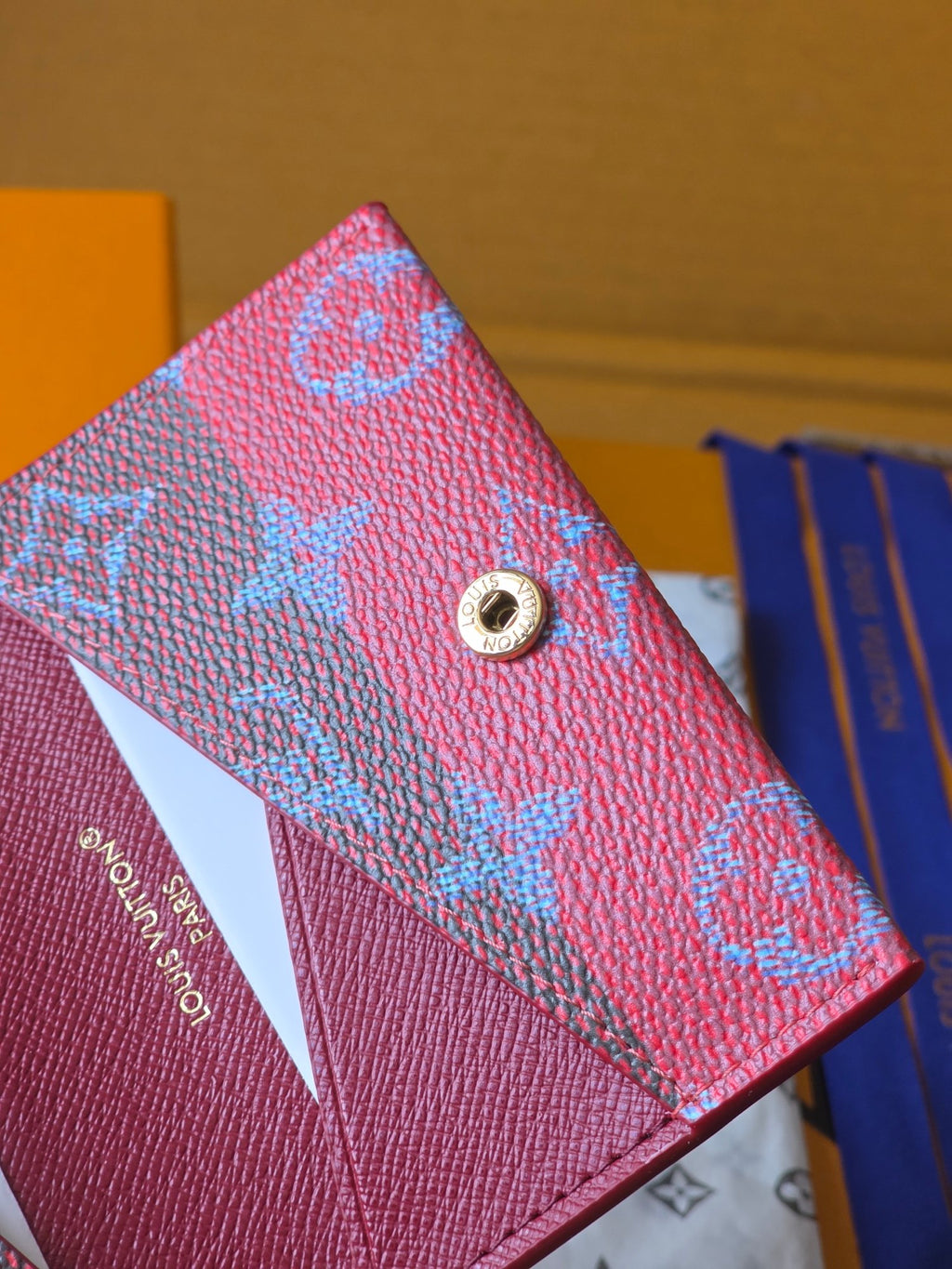 Small Louis Vuitton bag front close-up with silver-tone button and blue monogram pattern