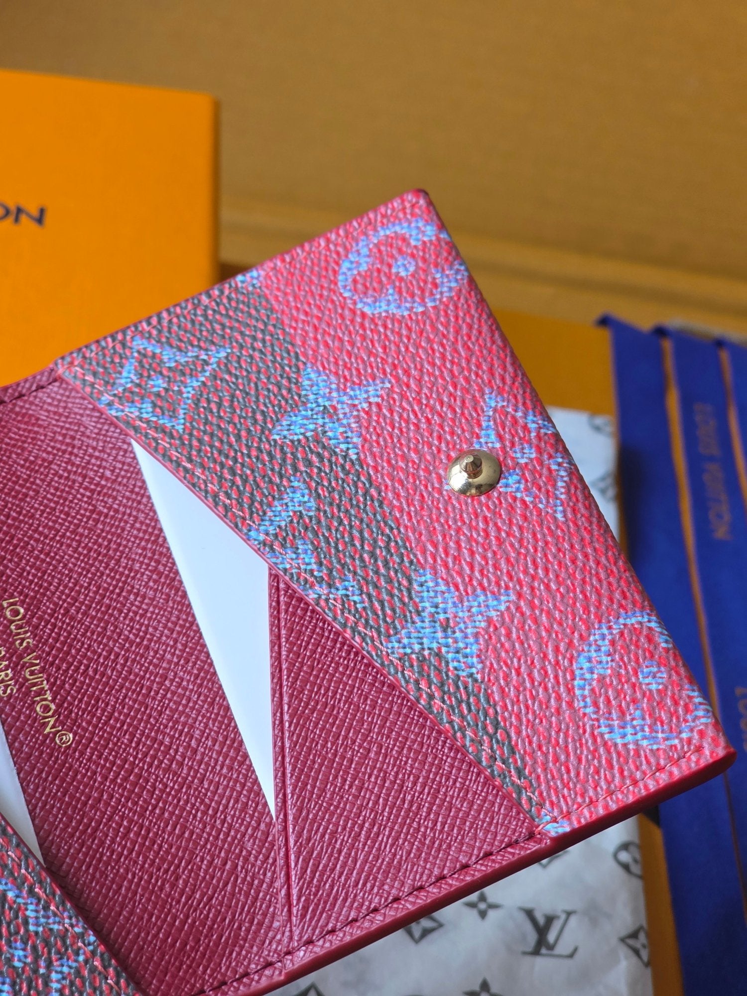 Small Louis Vuitton bag with blue monogram front, side view of button and edge seam