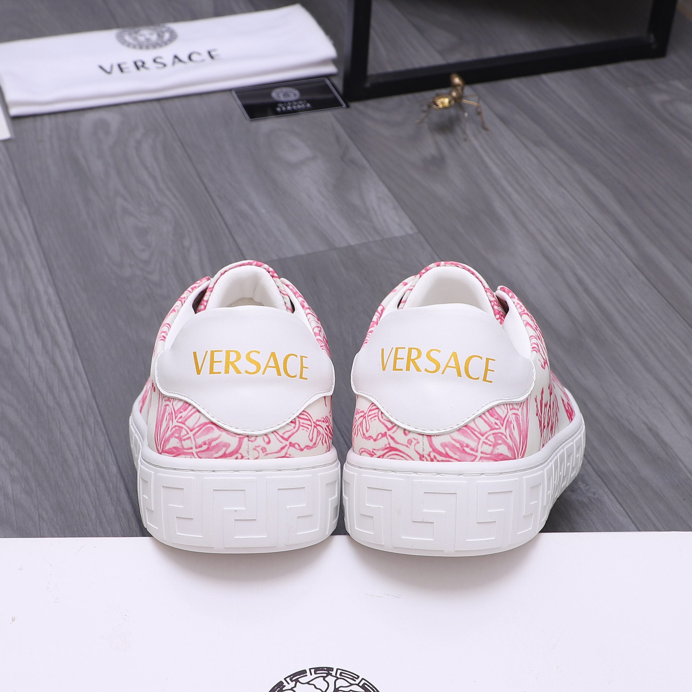 White heel sneakers with pink pattern and yellow logo lettering on back