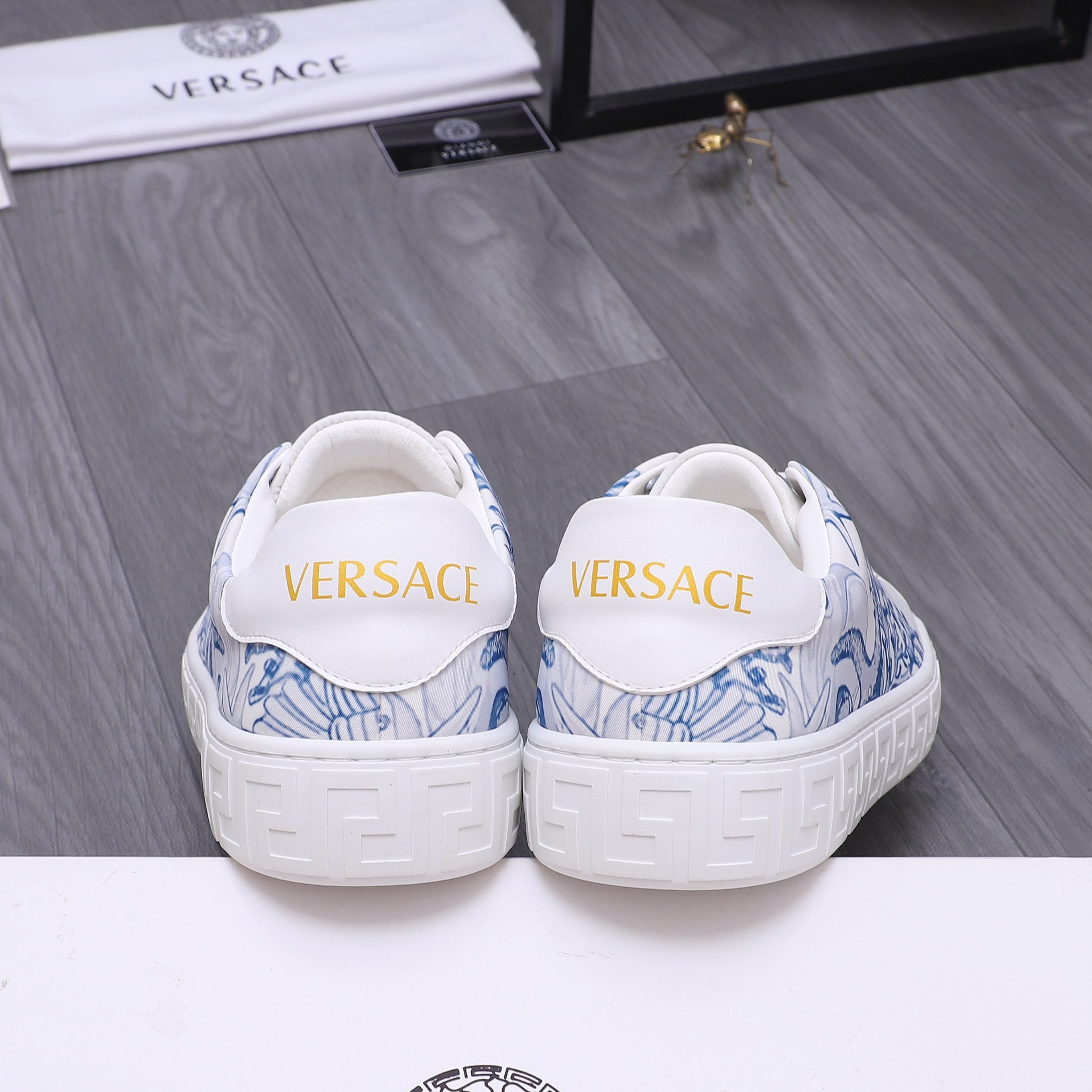 White Versace sneakers with blue pattern at heel, rear view, cushioned collar.