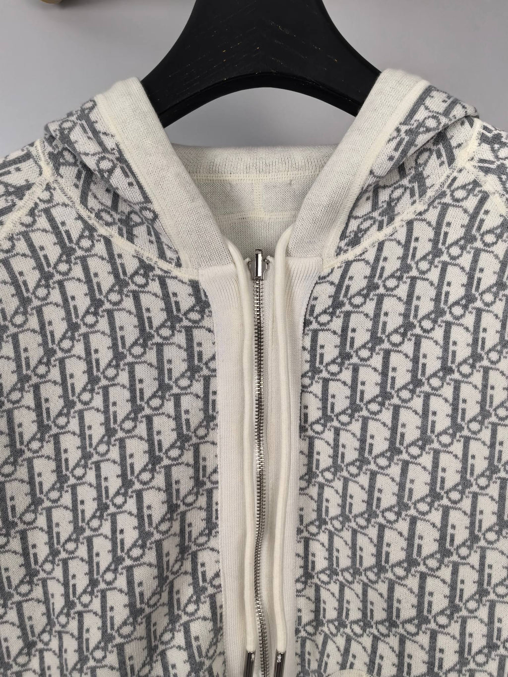 Zip-up hoodie close-up with monogram print, white hood lining, metal zipper
