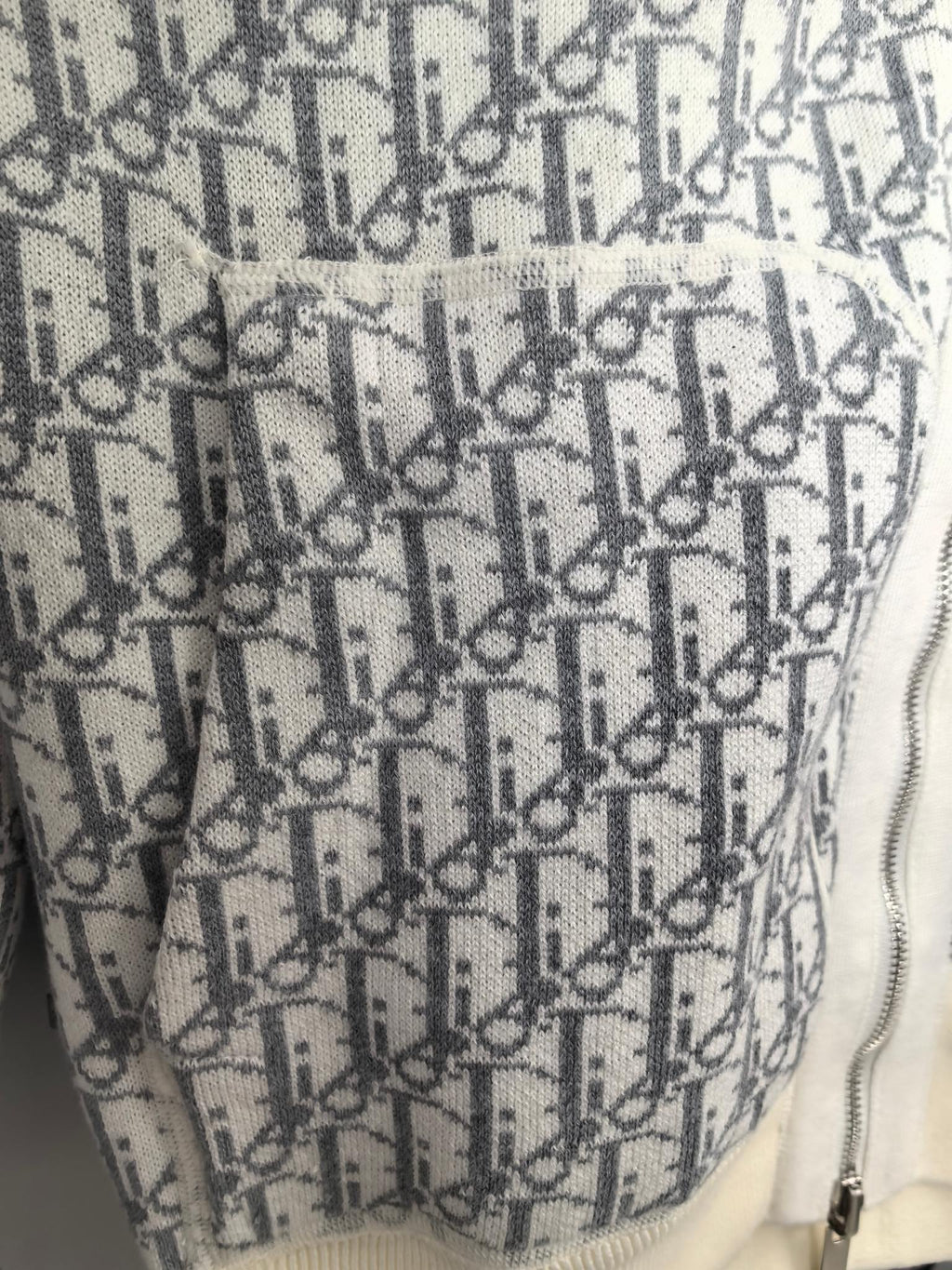 Monogram fabric panel detail on a zip-up hoodie, showing the zipper edge