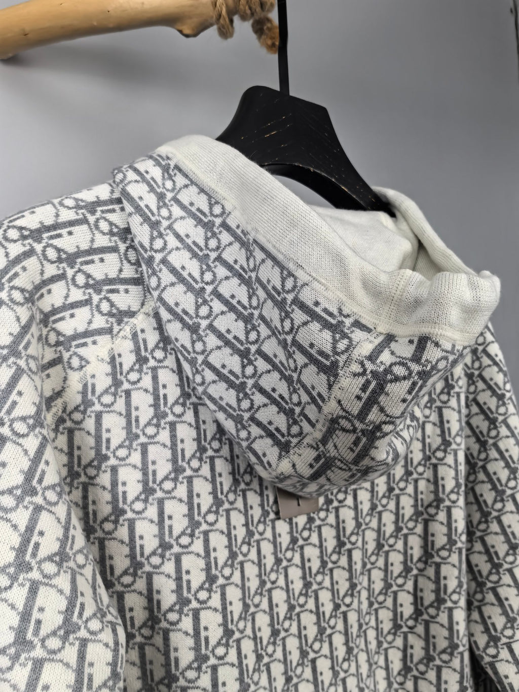 Hooded zip-up jacket in white with all-over monogram pattern, draped on hanger