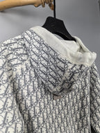 Hooded zip-up jacket in white with all-over monogram pattern, draped on hanger