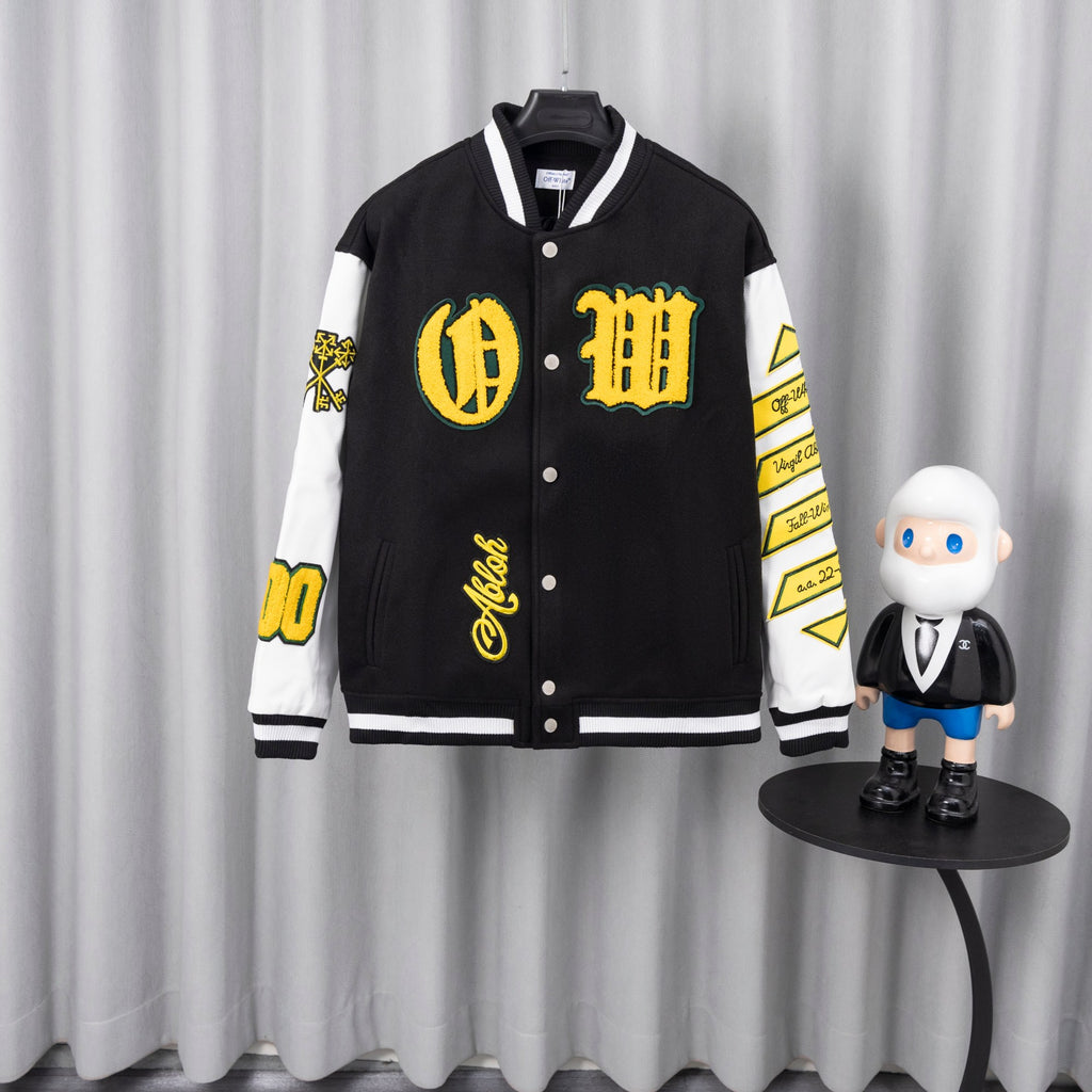 Black varsity jacket with white sleeves, yellow graphic patches, and snap-button front.