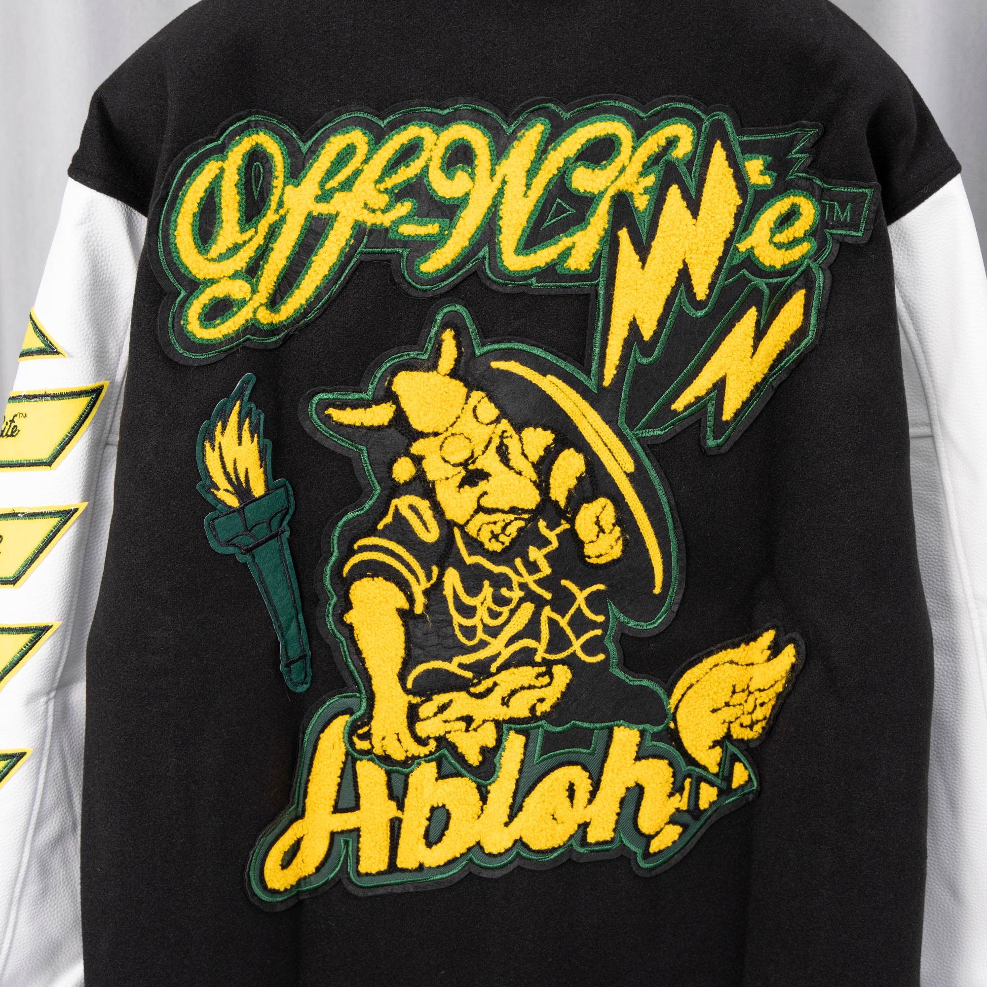 Black varsity jacket back with yellow cat graphic and 'Abloh!' text patch.