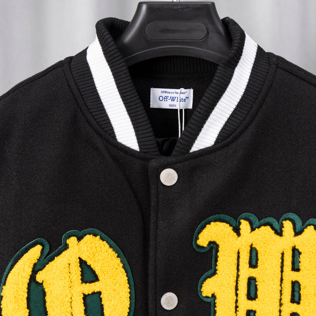 Black varsity jacket collar with white trim and yellow letter patches on front.