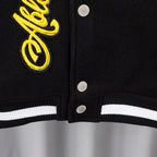 Hem and snap placket of black varsity jacket with white striped ribbed cuffs.