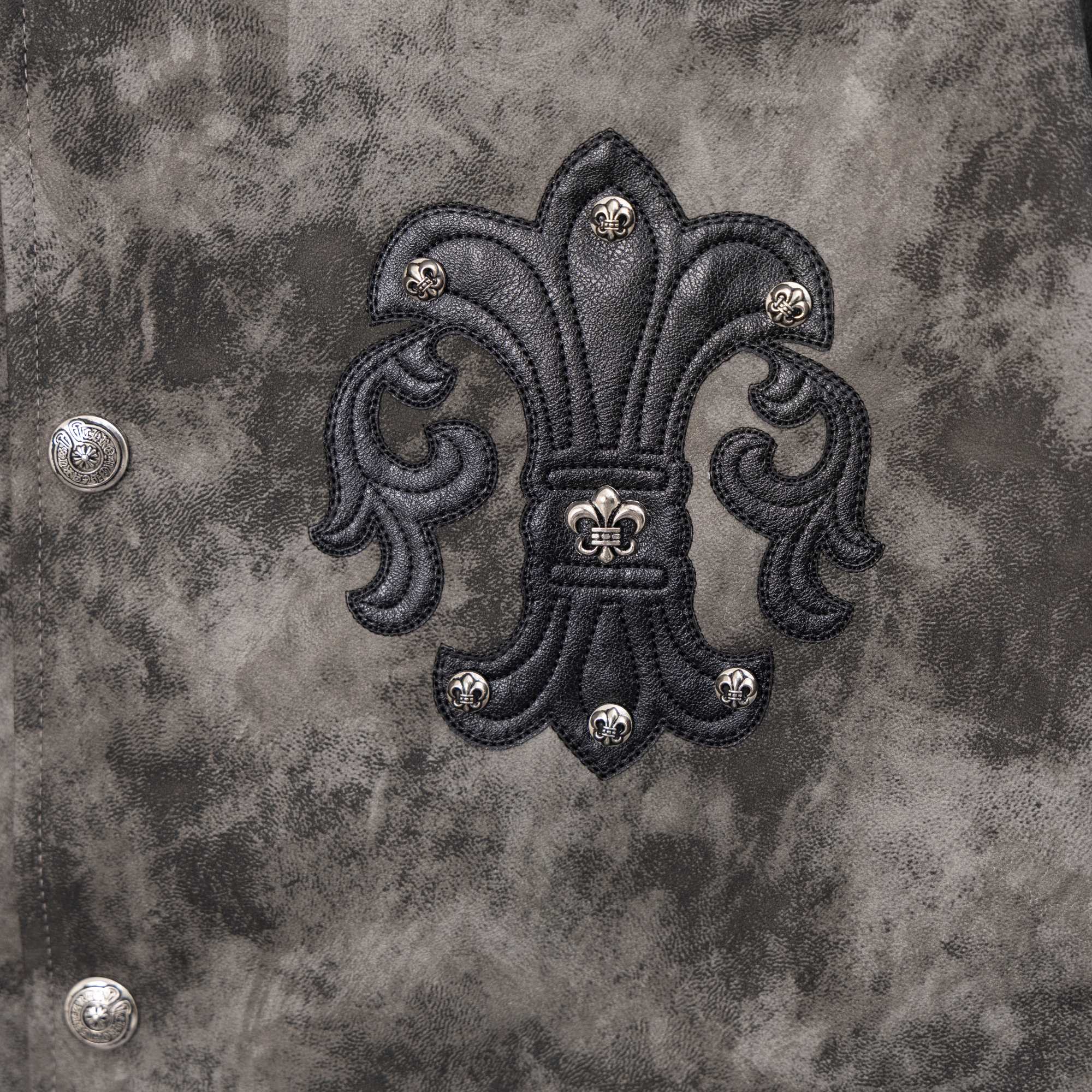 Close-up of dark gray jacket back with large black embroidered emblem and metal studs