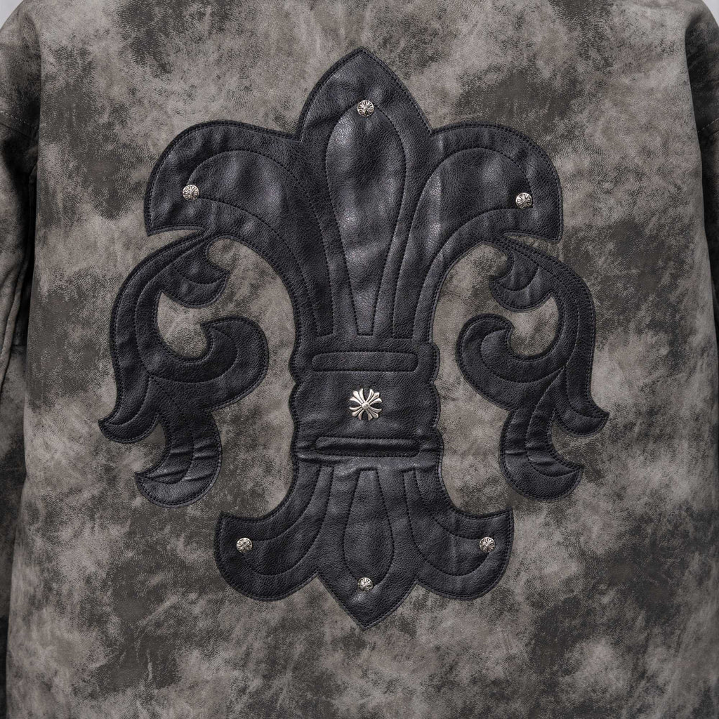 Close-up of dark gray jacket front with black embroidered fleur-de-lis emblem