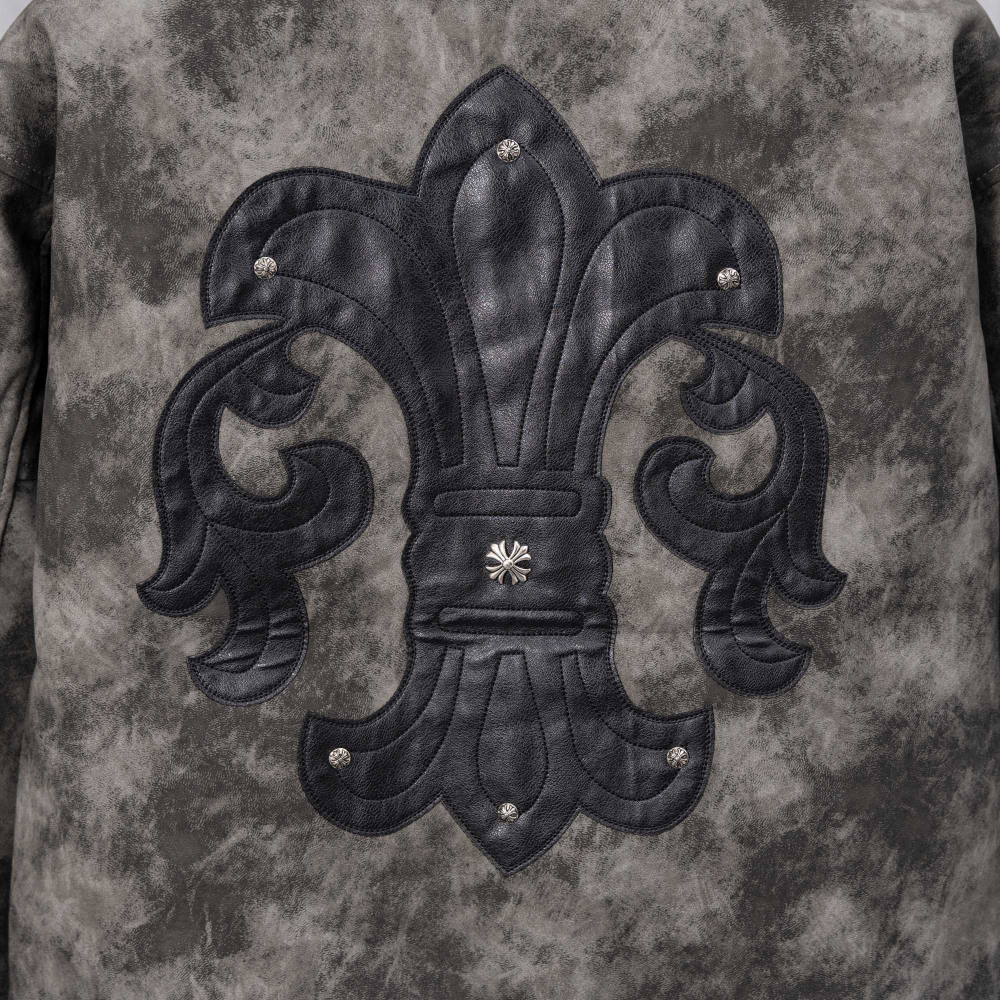 Close-up of dark gray jacket front with black embroidered fleur-de-lis emblem