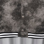 Close-up of dark gray jacket button placket with ribbed black-and-white hem stripe