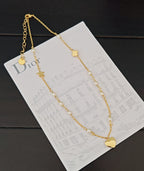 Gold-tone long necklace with heart charm and star accents on display card