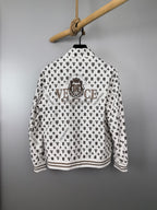 Long-sleeve zip jacket back view in white with dark monogram pattern and crest graphic.