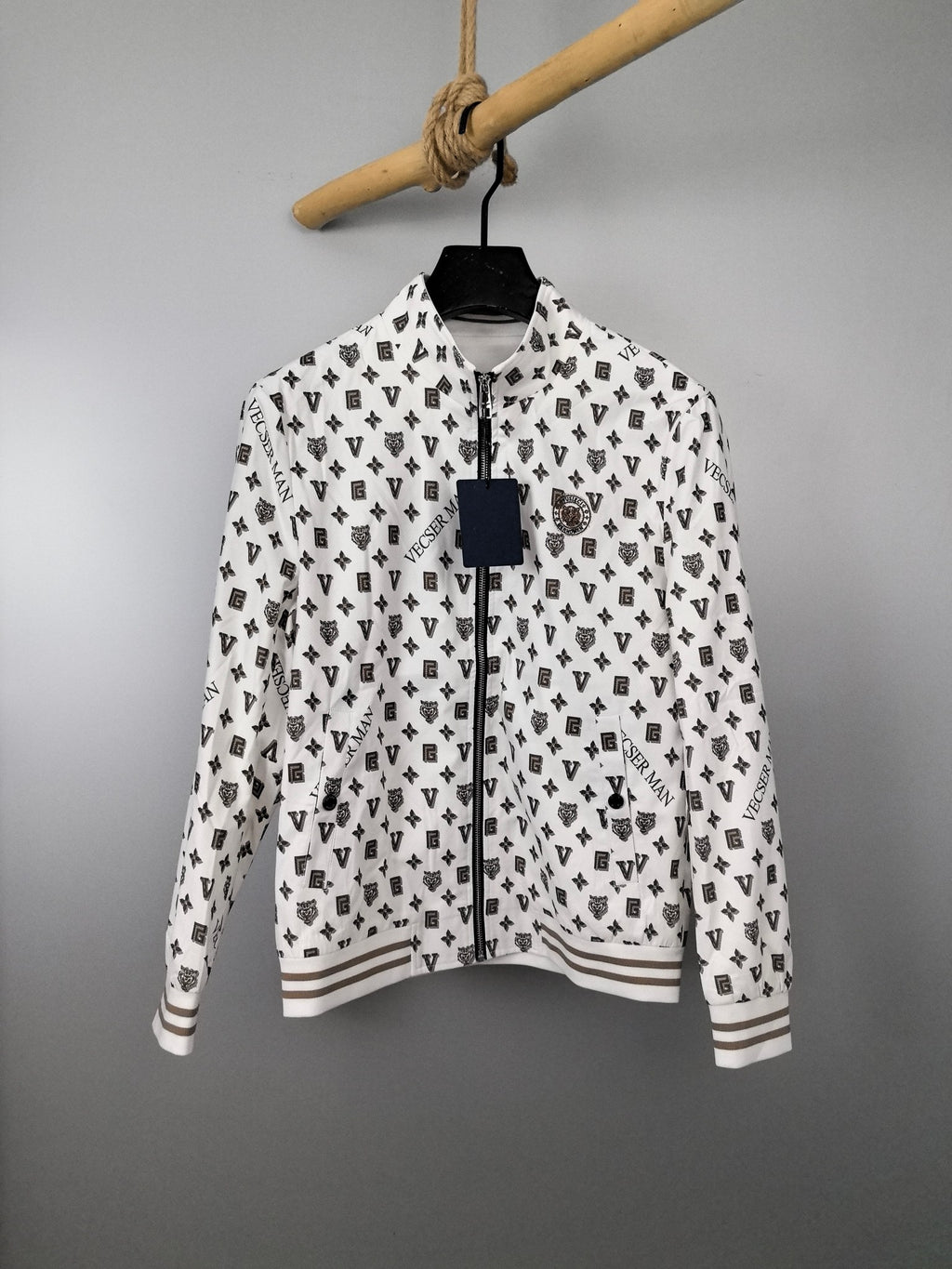 Long-sleeve zip jacket in white with repeating dark monogram print, ribbed cuffs.