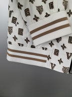 White jacket sleeve cuff with dark monogram print and tan-striped ribbed trim.
