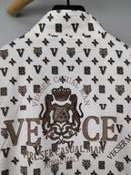 Long-sleeve jacket back close-up in white with large crest graphic over dark monogram print.