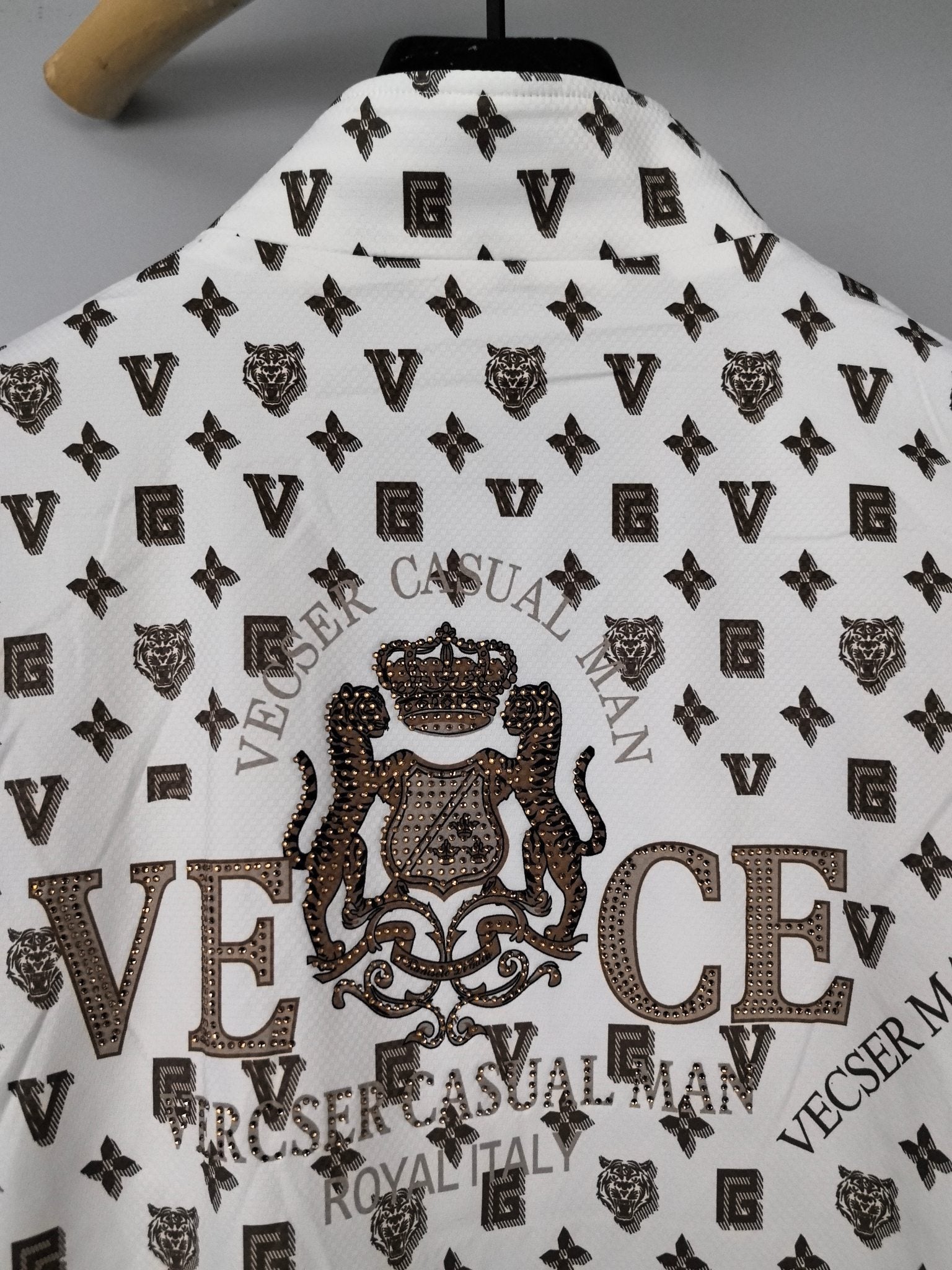 Long-sleeve jacket back close-up in white with large crest graphic over dark monogram print.
