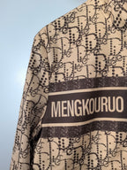 Beige patterned long jacket with MENGKOUROU stripe across upper front, close-up